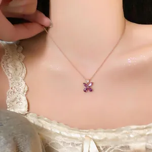 Close-up of elegant rose gold necklace with purple flower pendant on a woman's neck.