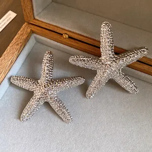 Detailed macro view of textured silver-colored starfish stud earrings in a jewelry box