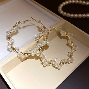 Detailed view of gold twisted hoop earrings with sparkling clear beaded embellishments