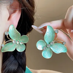 Close-up detail of mint green enamel butterfly stud earrings with zircon accents.
