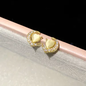 Dettaglio di orecchini a luna con pietra occhio di gatto a cuore e strass luminosi