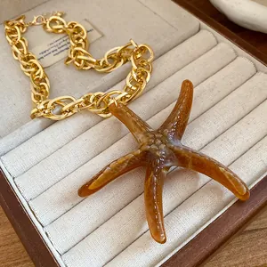 Close-up detail of amber acrylic starfish pendant with gold chunky link chain