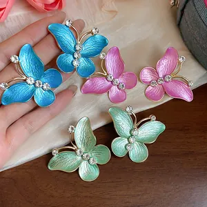 Detailed macro view of colorful oil drip butterfly earrings decorated with sparkling zircons