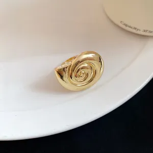 Macro view of a vintage style gold conch shell ring resting on a white ceramic plate