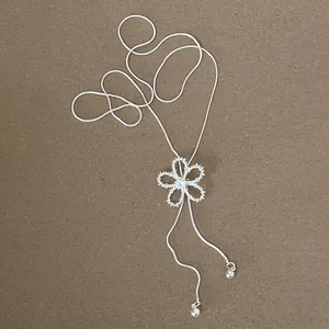 Detail view of a minimalist silver snake chain necklace with zircon flower pendant
