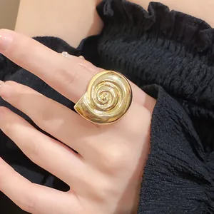 Detailed close-up view of vintage gold conch shell ring on hand with black ruffles