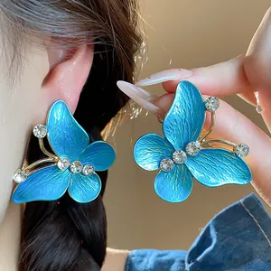 Detailed macro view of elegant blue enamel butterfly stud earrings with sparkling zircons.
