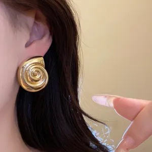 Vintage-style gold metallic conch shell earring showing a detailed spiral texture on model.