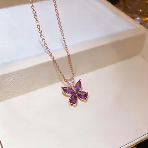 Close-up detail of an elegant rose gold necklace with a purple zircon flower pendant