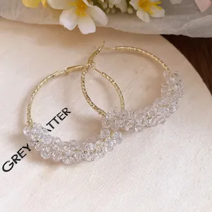Detail showing elegant gold-toned hoop earrings with clear faceted crystal beads.