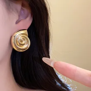 Detail view of retro gold conch shell earring showing metallic texture and spiral design