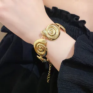 Close-up of a vintage gold-toned seashell spiral link bracelet on a woman's wrist
