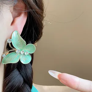 Detail showing a light green enamel butterfly stud earring with clear rhinestones
