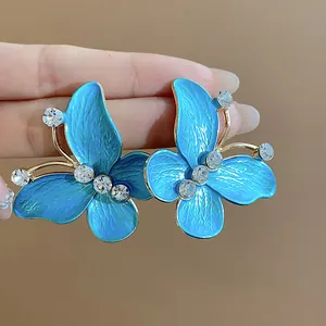 Detailed view of blue oil-drop butterfly earrings with sparkling zircon accents