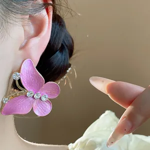 Macro view of elegant purple butterfly stud earrings with sparkling zircon on ear