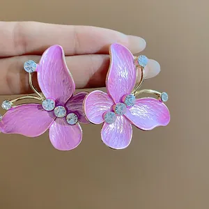 Close-up of pink butterfly stud earrings featuring sparkling zircon and enamel finish