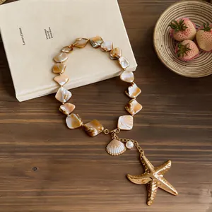 Detailed view of irregular shell bead necklace with a gold starfish pendant and pearl