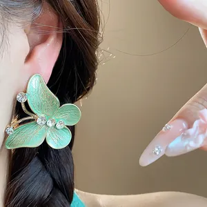 Detail shot of a green enamel butterfly stud earring with sparkling zircon accents.