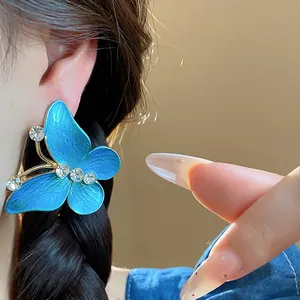 Macro view of blue butterfly oil-drop stud earring with shimmering zircon accents
