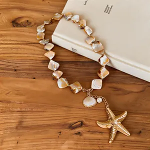 Detailed view of handmade shell bead necklace with golden starfish and pearl pendants