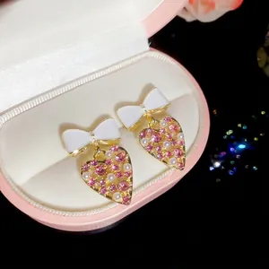 Pendientes de corazón con lazo blanco y cristales rosas en caja de joya