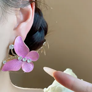 Close-up detail of pink enamel butterfly stud earring with sparkling zircon accents on ear.