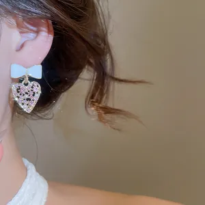 Vista detallada de elegantes pendientes de lazo con corazon de strass rosa en la oreja