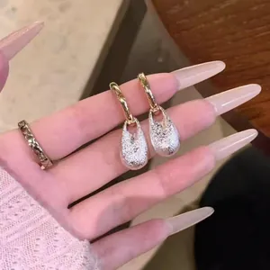 Primo piano dettagliato di orecchini a cerchio dorati con eleganti pendenti a goccia