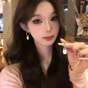 Dettaglio degli orecchini vintage con ciondolo a goccia indossati da una modella asiatica.