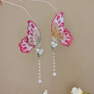 Close-up view of elegant embroidery butterfly earrings with hanging white pearl tassels