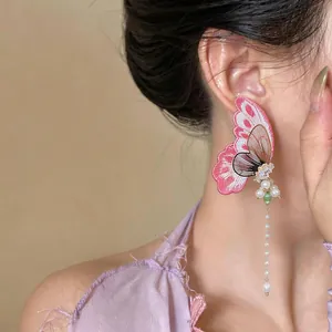 Exquisite macro detail of pink embroidery butterfly earring featuring a long pearl tassel drop