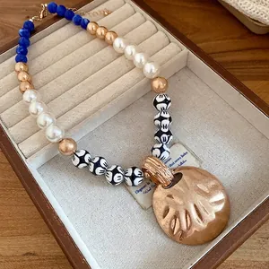 Elegant vintage pearl and ceramic beaded necklace with a hammered round gold pendant