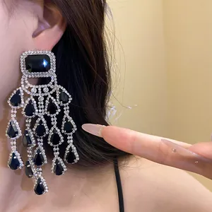 Detailed view of silver-toned chandelier earrings with black stones and sparkling crystals.