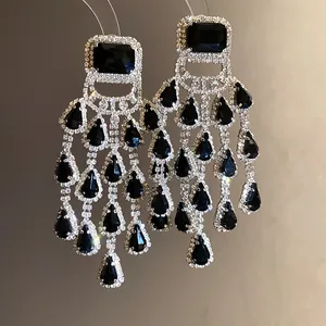 Macro shot of silver-toned chandelier earrings with black teardrop stones and pave detailing
