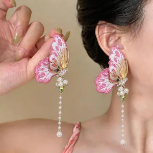 Close-up view of elegant butterfly embroidery earrings featuring delicate pearl tassels.