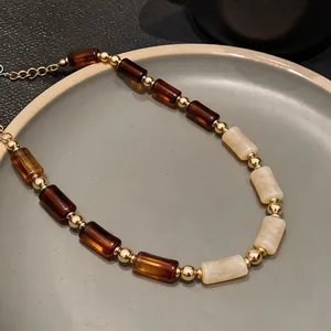 Macro detail of Maillard style acrylic beaded necklace with vintage gold accents.