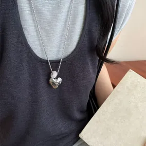 Silver heart necklace with natural stone bead worn by a model in a casual setting