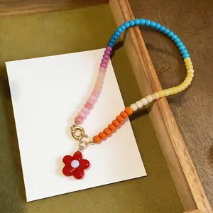 Close-up of colorful glass beaded necklace featuring a vibrant red flower pendant