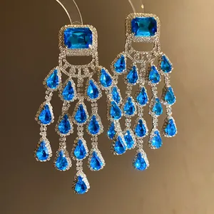 Close-up of elegant chandelier earrings with blue teardrop stones and rhinestones