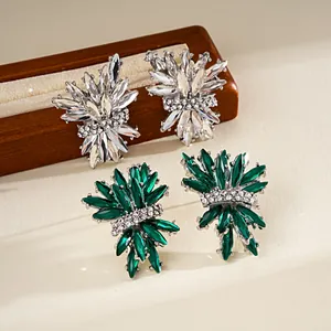 Detailed shot of emerald and clear crystal firework stud earrings on wooden stand