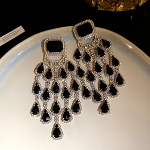 Detailed macro view of elegant black teardrop tassel earrings with sparkling rhinestone studs