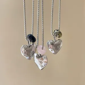 Detailed shot of silver heart necklaces with various natural gemstones and square links