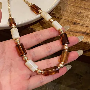 Close-up of vintage Maillard style necklace with amber and cream acrylic beads held in hand