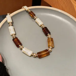 Close-up of retro brown and marble white acrylic beaded necklace on ceramic plate