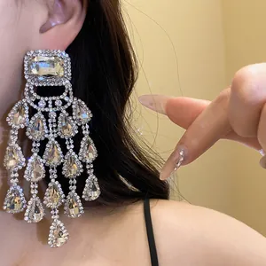 Detailed view of silver needle rhinestone waterdrop tassel earrings worn on ear.