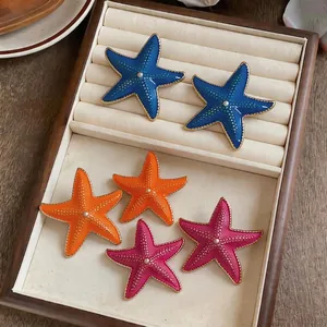 Enamel starfish stud earrings with pearl centers for a vibrant beach vacation look
