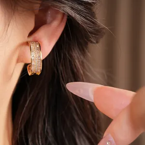 Close-up view of a gold-plated wrinkled hoop clip-on earring with cubic zirconia on ear.