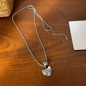 Close-up of heart pendant with 'Eternal my love' engraving and spotted natural stone