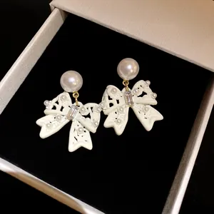 Close-up of elegant white bow earrings with pearls in a velvet jewelry box