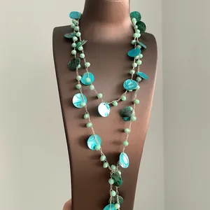 Dettaglio di una collana bohémienne con dischi di conchiglia turchesi e perline.
